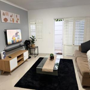 Una sala de estar con un sofá y un televisor en Cozy Retreat with a Pool!, en Cape Town