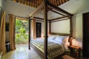 een slaapkamer met een hemelbed en een raam bij Villa Bukit Kaja Kauh in Pemuteran +63 foto's