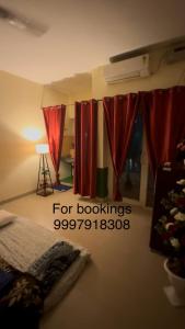 une pièce avec des rideaux rouges et une table avec une lampe dans l'établissement Peaceful Gopala near Premanand Maharaj Ji, à Vrindavan