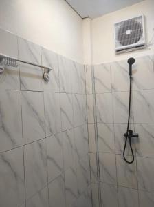 a bathroom with a shower with white marble tiles at Embun Pagi Alami in Telukladang
