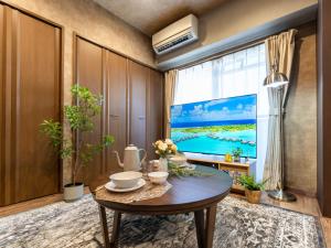 a living room with a table and a large screen tv at MY STORY Classic 405-瓦町駅徒歩6分 in Shimminatomachi