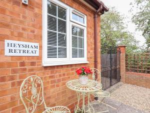 a table and chairs with a vase of flowers on it at Heysham Retreat in Evesham