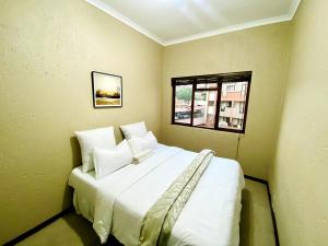 ein Schlafzimmer mit einem großen weißen Bett mit einem Fenster in der Unterkunft Sandton Skyline Suite - 2 Bedroom Apartment in Sandton