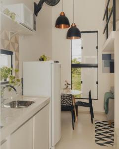 Una cocina con un refrigerador blanco y una mesa. en Loft Aconchegante & bem localizado II, en Santo Antônio dos Prazeres