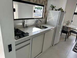 Una cocina blanca con fregadero y refrigerador. en Loft Aconchegante & bem localizado II, en Santo Antônio dos Prazeres 6 fotos más