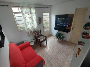 un salon avec une chaise rouge et une télé dans l'établissement Casa em Tiradentes, à Tiradentes