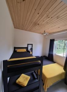 two beds in a room with a wooden ceiling at Kitnet dos netos in Ubatuba