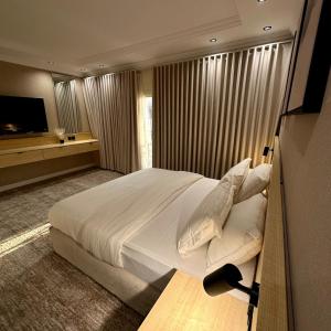 a bedroom with a large white bed and a television at نسيم الحرم 2 in Ash Shishah