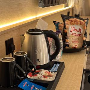 a tea kettle on top of a counter with snacks at نسيم الحرم 2 in Ash Shishah