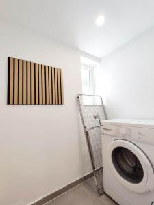 une machine à laver blanche dans une pièce avec un tableau dans l'établissement Flair-Apartments 'SALZ & FLAIR' nähe Altstadt, 450 m Bahnhof, für Urlaub oder Geschäftsreise, separater Eingang, 24 Std Check-in,WLAN, 55 Zoll-Fernseher, Streaming, Küche, Regendusche, 1 Doppelbett, 1 Schlafsofa, à Bad Salzuflen 15 autres photos