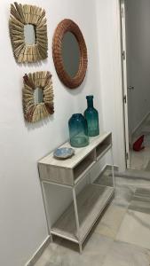 a table with a vase and a mirror on a wall at La casa del mar in Zahara de los Atunes