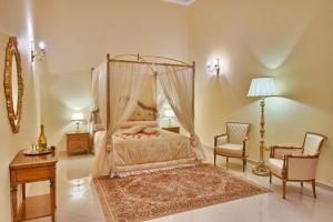 a bedroom with a canopy bed and two chairs at Castello Conti Filo in Torre Santa Susanna