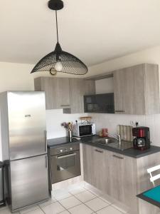 a kitchen with a stainless steel refrigerator and a microwave at Maeva 7 in Guidel