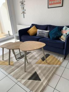 a living room with a blue couch and two tables at Maeva 7 in Guidel