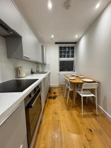 une cuisine avec des armoires blanches et une table en bois dans l'établissement En Suits room with your own bathroom and toilet, à Londres