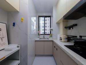 a white kitchen with a sink and a window at Annie Apartment 2105 in Kunming