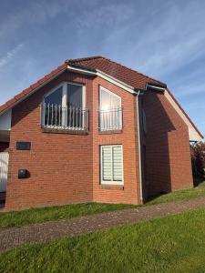 ein Backsteinhaus mit zwei seitlichen Fenstern in der Unterkunft Neu Ferienhaus Sielbude Neßmersiel mit Garten und Wallbox allergikerfreundlich in Neßmersiel
