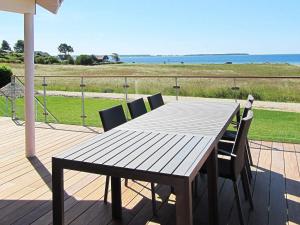 ein Holztisch und Stühle auf einer Terrasse mit Blick auf das Meer in der Unterkunft Luxury Retreat in Ebeltoft - By Traum Ferienwohnungen in Ebeltoft