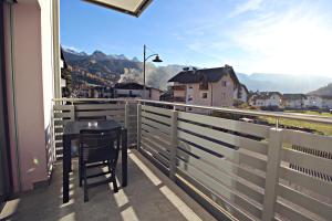 a chair on a balcony with a view of a city at Guest House Cemin in Predazzo