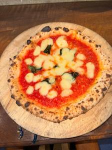 a pizza sitting on a wooden plate on a table at HANABI棟 8人宿泊 サウナあり ペット不可 - Base棟 4人宿泊 サウナなし ペット可 - 貸切で最大12名宿泊OK in Katori
