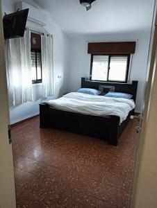a bedroom with a bed and two windows at צימר טיילת הכלנית in Ma'alot Tarshiha