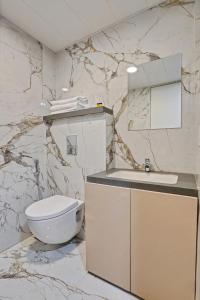 a white bathroom with a toilet and a sink at Charvi Suites in Pune