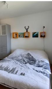 a bed in a bedroom with two pictures on the wall at Nid des Angles - Cœur de station vue Lac & Montagne in Les Angles