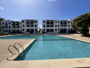 a swimming pool in front of a building at Tramontana -Apartamento con piscina junto la playa in Arenal d'en Castell