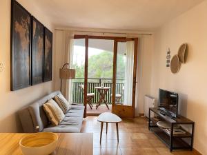 a living room with a couch and a television at Tramontana -Apartamento con piscina junto la playa in Arenal d'en Castell