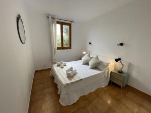 a white bedroom with a bed and a window at Tramontana -Apartamento con piscina junto la playa in Arenal d'en Castell +39 photos