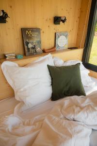 a bed with white sheets and pillows in a room at Parcel Tiny House Vallée, près de Verdun in Rarécourt