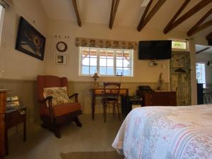 a bedroom with a bed and a chair and a table at Buttercup Cottage in Nottingham Road