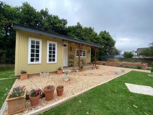 a small yellow house with potted plants in a yard at Buttercup Cottage in Nottingham Road