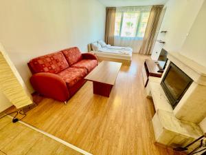 a living room with a red couch and a television at Todorini Kuli Apartments in Bansko