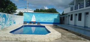 a swimming pool with a sailboat on a wall at Apartamentos grigri in Río San Juan