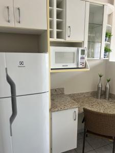 a kitchen with a white refrigerator and a microwave at Apartamento perto do centro da Cidade in Campo Grande