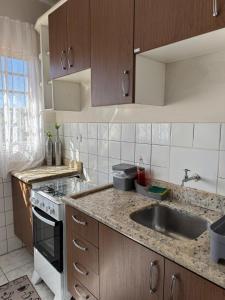 a kitchen with a sink and a stove at Apartamento perto do centro da Cidade in Campo Grande