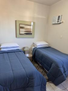 two beds in a room with blue sheets at Apartamento perto do centro da Cidade in Campo Grande +1 photo