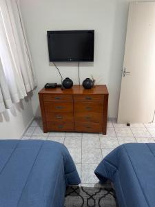 a bedroom with two beds and a television on a dresser at Apartamento perto do centro da Cidade in Campo Grande