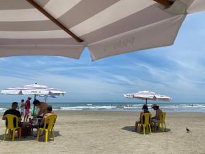 un grupo de personas sentadas bajo sombrillas en la playa en Temporada top n538, en Praia Grande