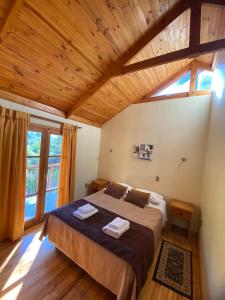 Un dormitorio con una cama grande con techo de madera. en Cabañas Parque Almendro, en San José de Maipo