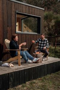 two people sitting on the deck of a tiny house at Parcel Tiny House Regagnas- au pied de la Sainte Victoire in Trets