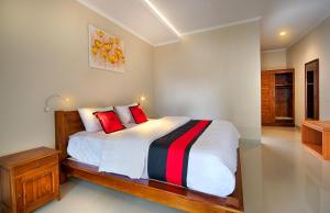 a bedroom with a large bed with red pillows at Puri Canggu Villas & Rooms in Canggu