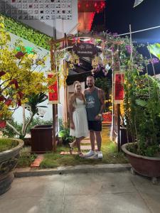 un homme et une femme debout devant un jardin dans l'établissement Homestay Gio bien, à Ấp Ngọc Hải