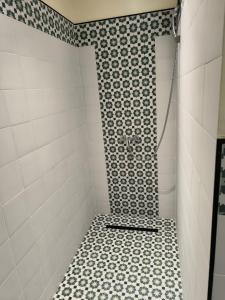 y baño con ducha y azulejos blancos y negros. en YaYaCaSa, en Tánger 6 fotos más