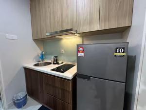 a small kitchen with a refrigerator and a sink at Cozy Stays Studio - Kozi Square Kuching in Kuching