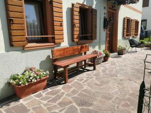 a wooden bench sitting outside of a building with flowers at Casa Borgovillanuova in Laggio