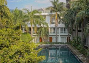 een appartementencomplex met een zwembad en palmbomen bij Narayana Sanctuary Resort by SALVUS in Rishīkesh