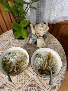 une table avec deux assiettes de nouilles et une théière dans l'établissement Homestay Gio bien, à Ấp Ngọc Hải
