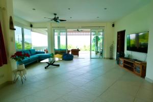 un salon avec un canapé bleu et une télévision dans l'établissement Luxury Seaview Villa, Infinity Pool, Sunset, à Karon Beach